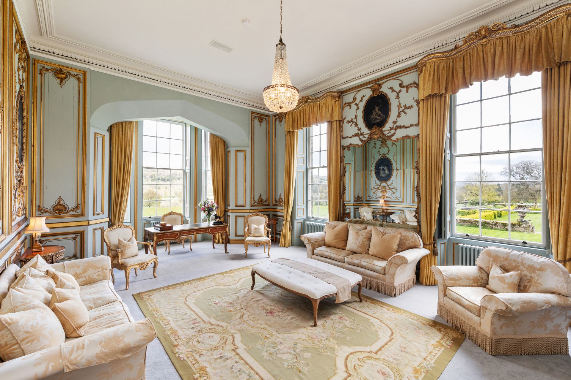 Sitting room with gold drapes and a chandelier