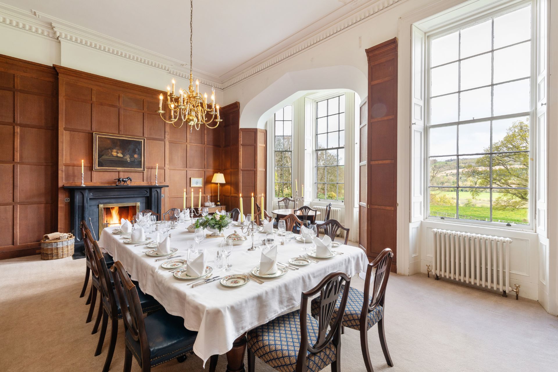 Wood panelled dining room with navy chairs and a cream and navy patterned rug.