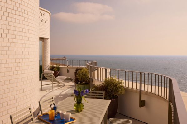 Curved balcony with brown railings and a view of the sea