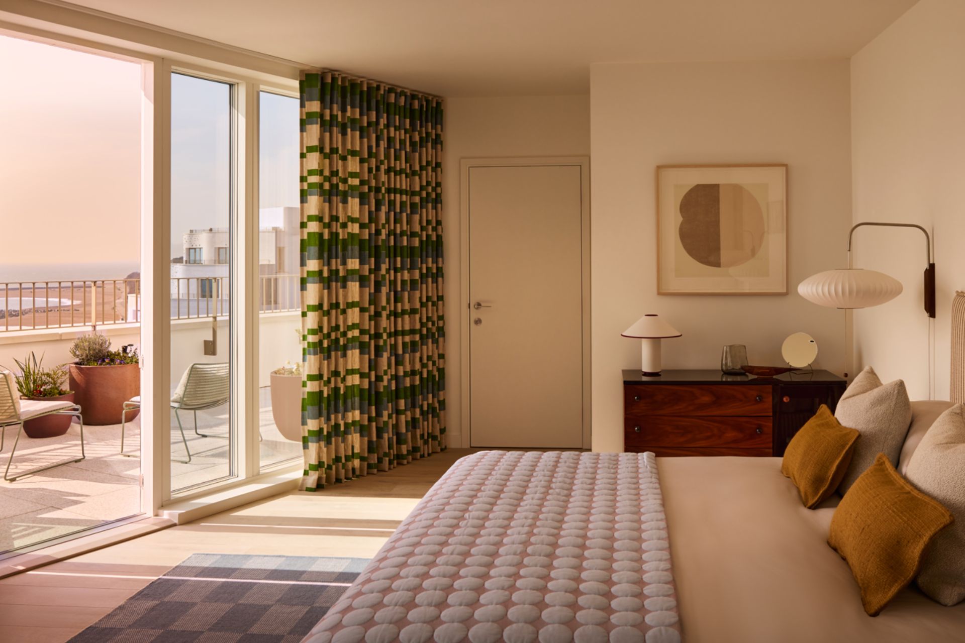 Bedroom with cream walls, burnt orange cushions, and sea views