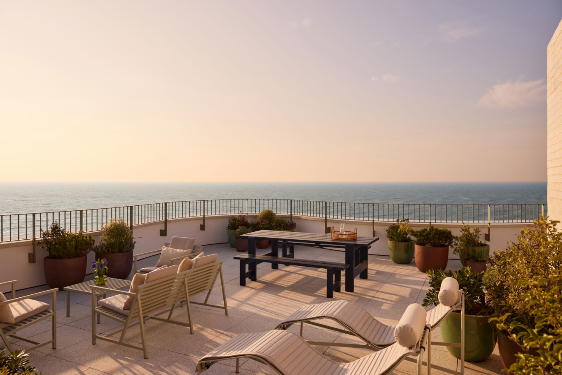 Large ocean view terrace with wooden chairs, sun loungers and a dining table