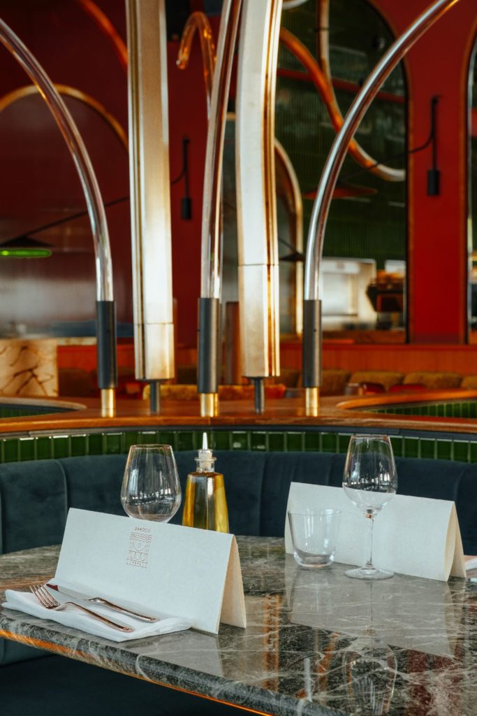 Restaurant with marble tables, yellow crushed velvet seating and brass archways.