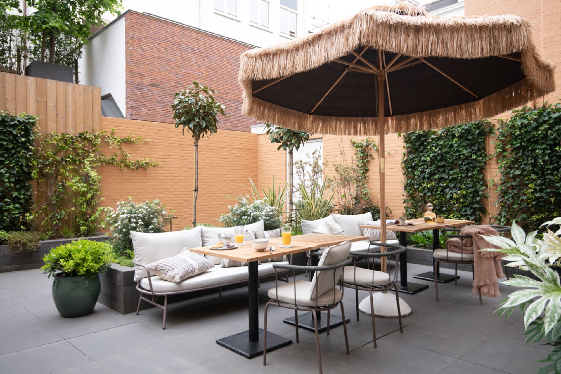 Garden with fringed parasol and large white sofa.