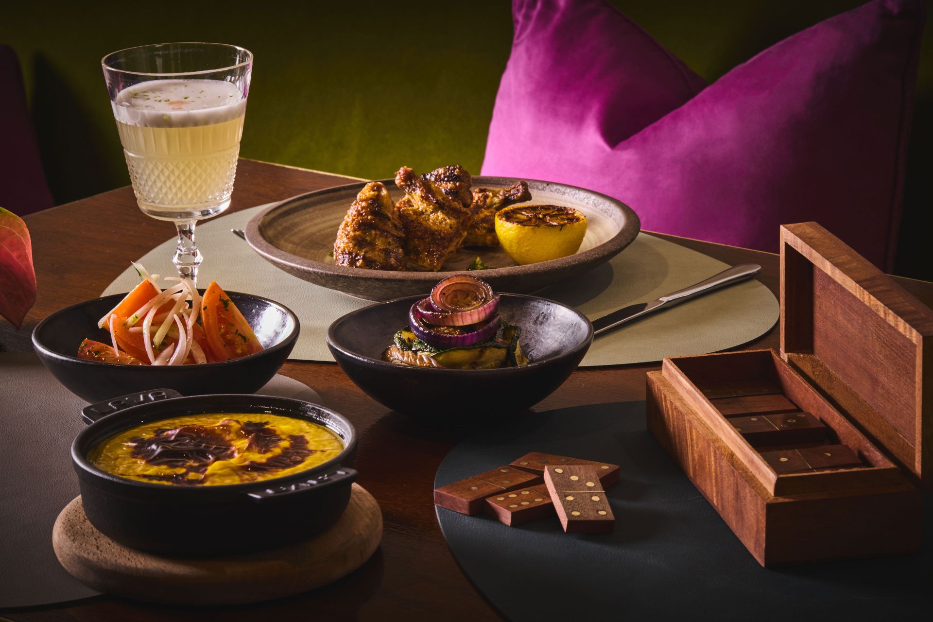Chilean dishes served on a dark wooden dining table with a purple cushion in view behind.