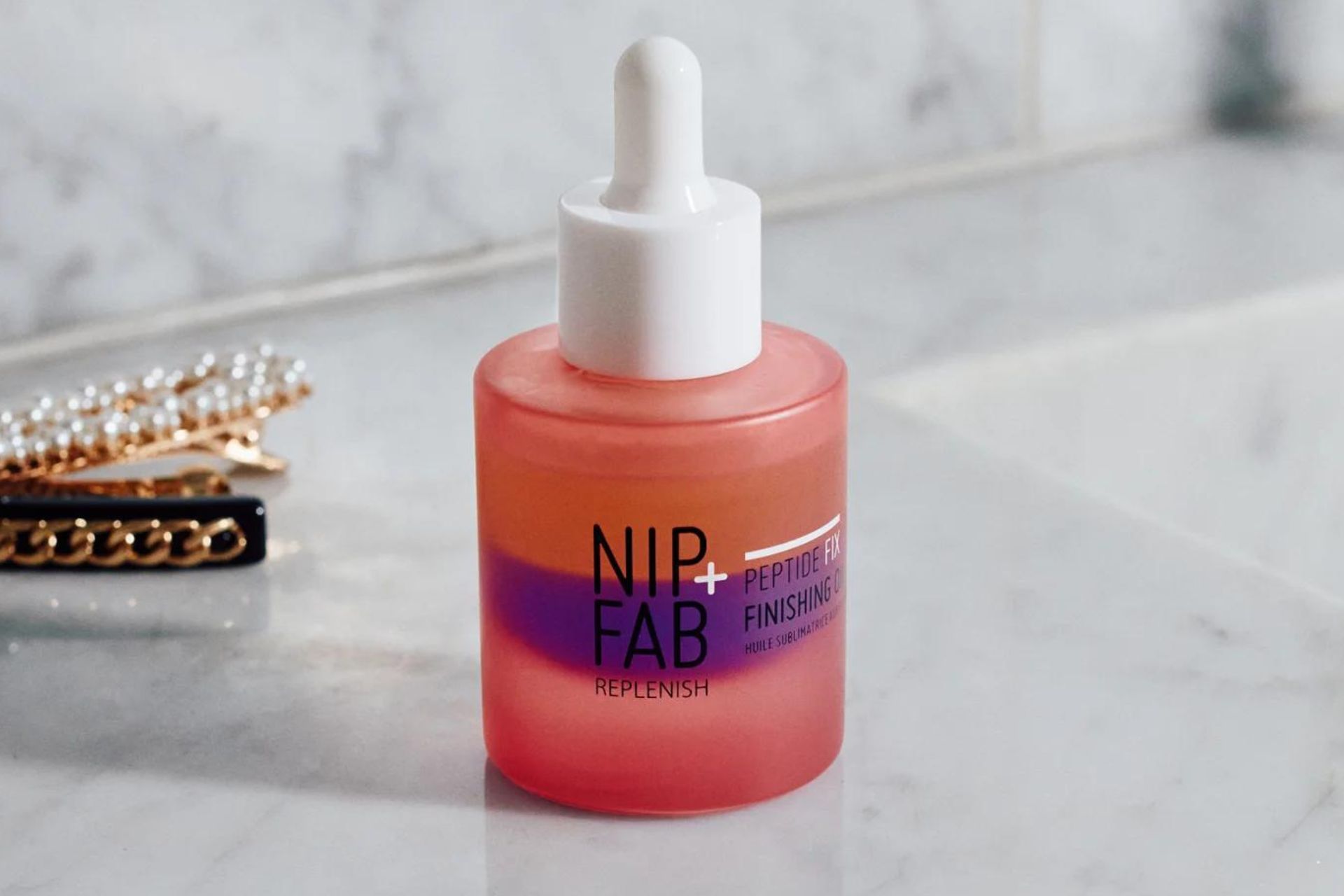 Pink and purple NIP+FAB serum on a white marble surface.