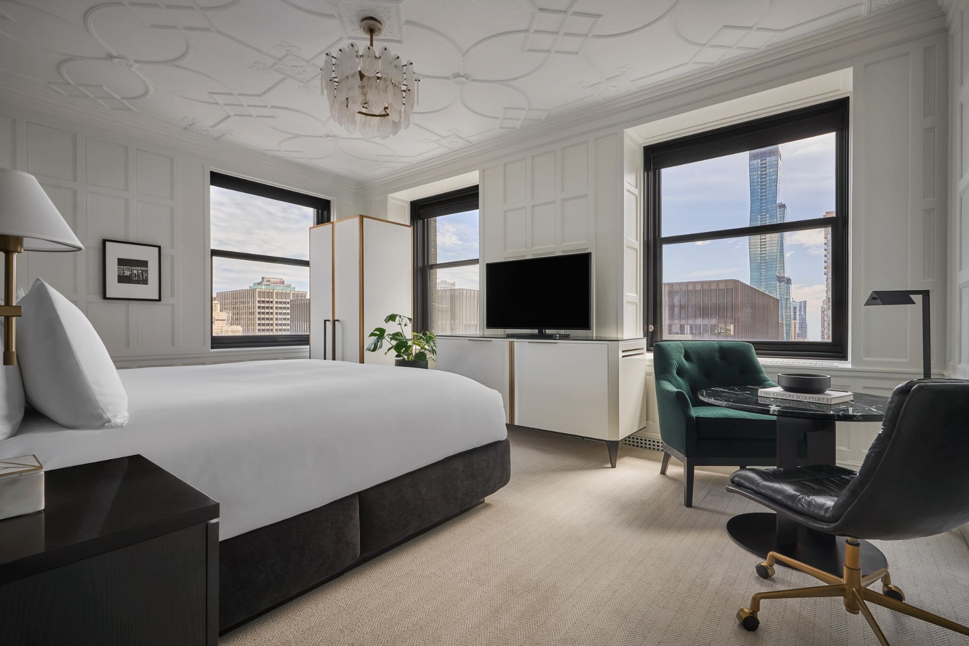 Hotel bedroom with black fixtures, ceiling cornicing and white walls.