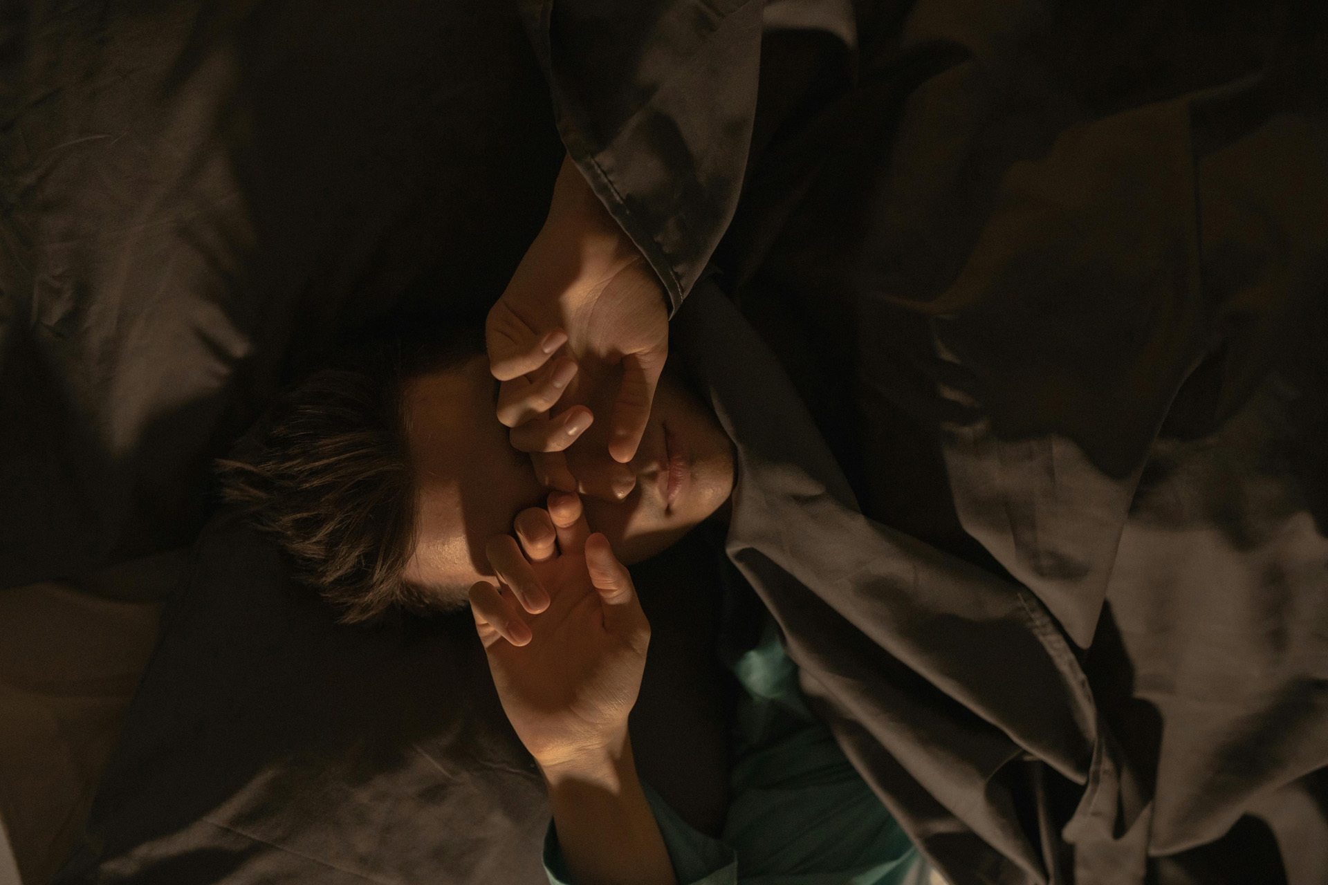 A man rubbing his eyes in bed