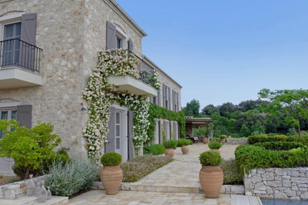 Exterior of Villa Koukus, a stone property with flower garlands over the doorway