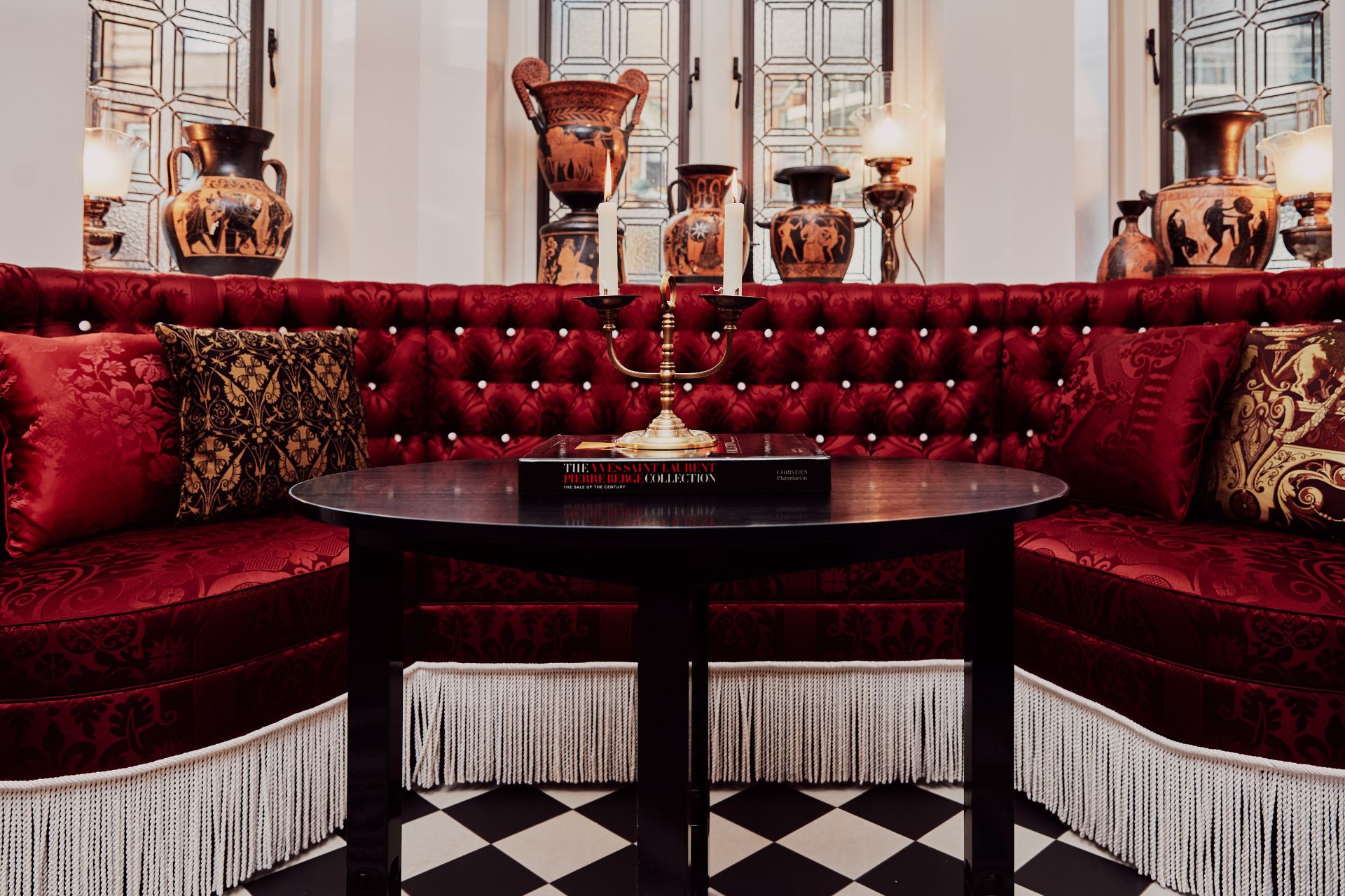 Hotel lobby with red velvet seating and black and white flooring.