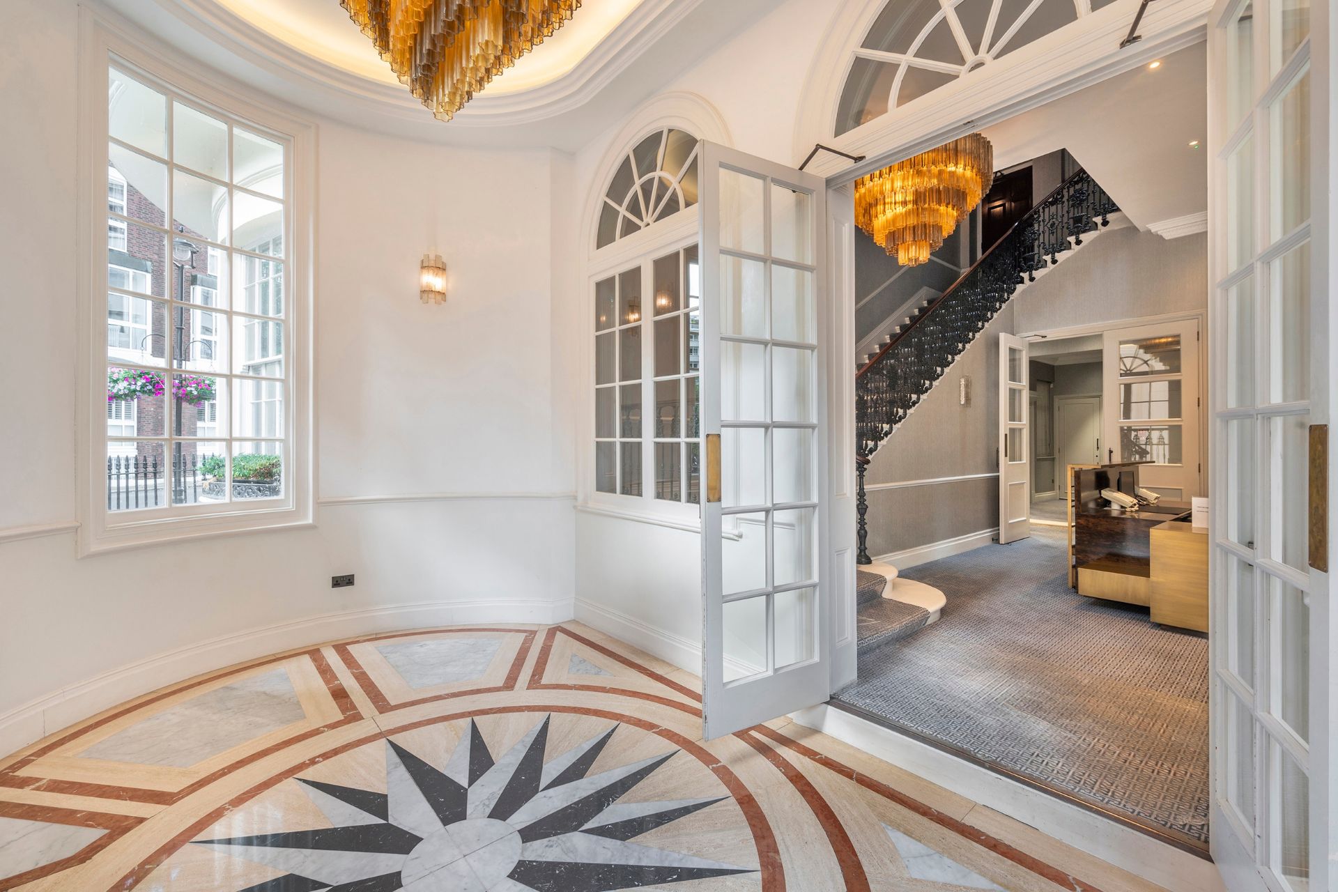 Hallway with chandeliers, tiled flooring and fanlight windows.