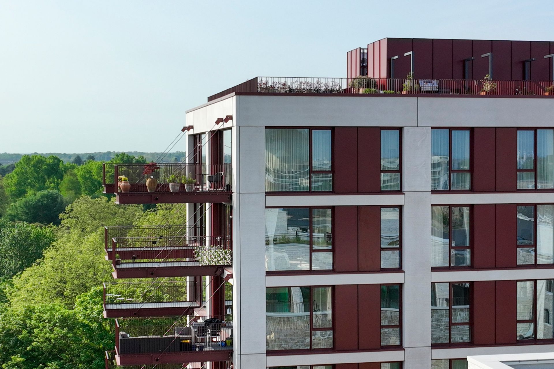 Apartment block with red balconies and a leafy setting