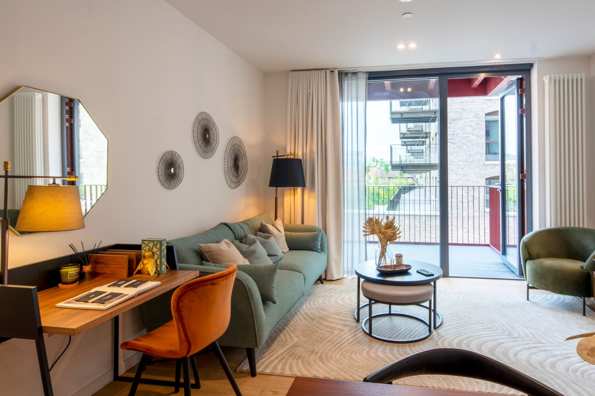 Study with forest green velvet sofa, orange armchair and balcony
