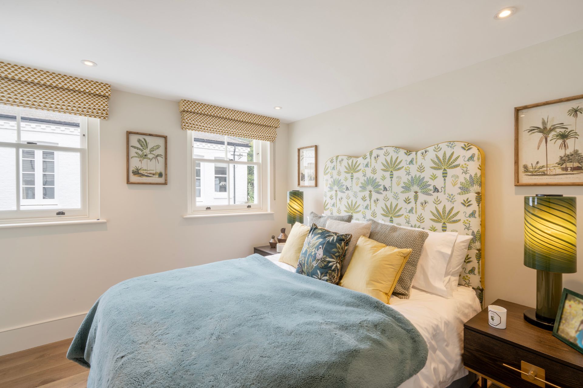 Bedroom with patterned headboard, blue bedspread and yellow cushions.