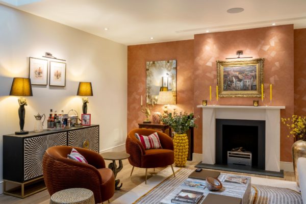 Living room with fireplace, red armchairs and a terracotta feature wall.