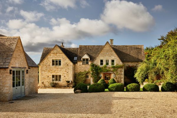 Cotswolds house with stone outbuildings and a gravel driveway.