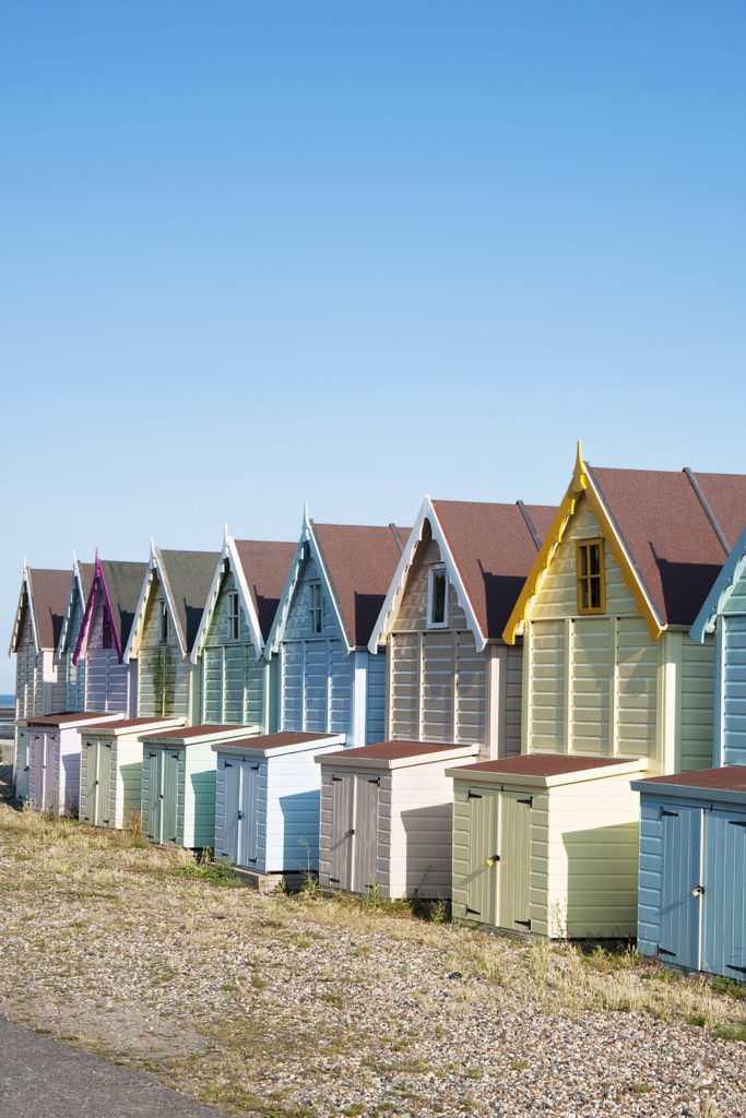 A row of pastel colored beach huts at West Mersea, Essex, UK.