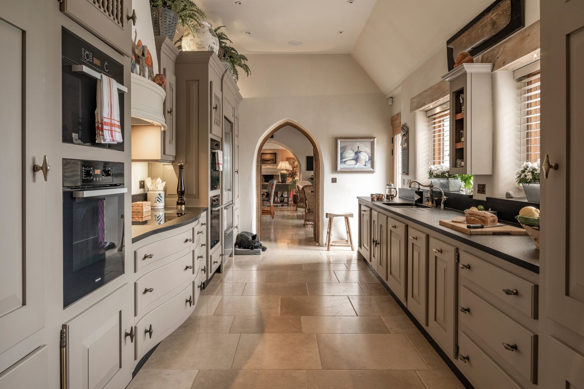 Country kitchen with taupe cabinets and an arched doorway