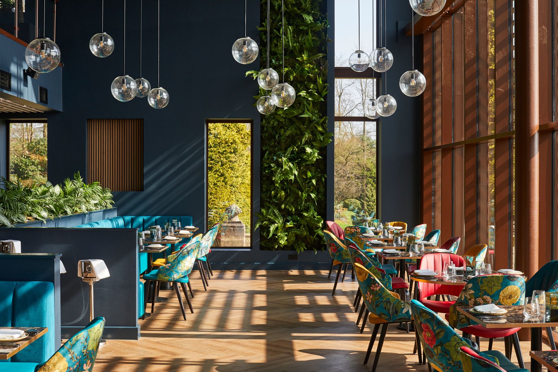 Restaurant with navy blue walls, floral chairs and glass pendant lights