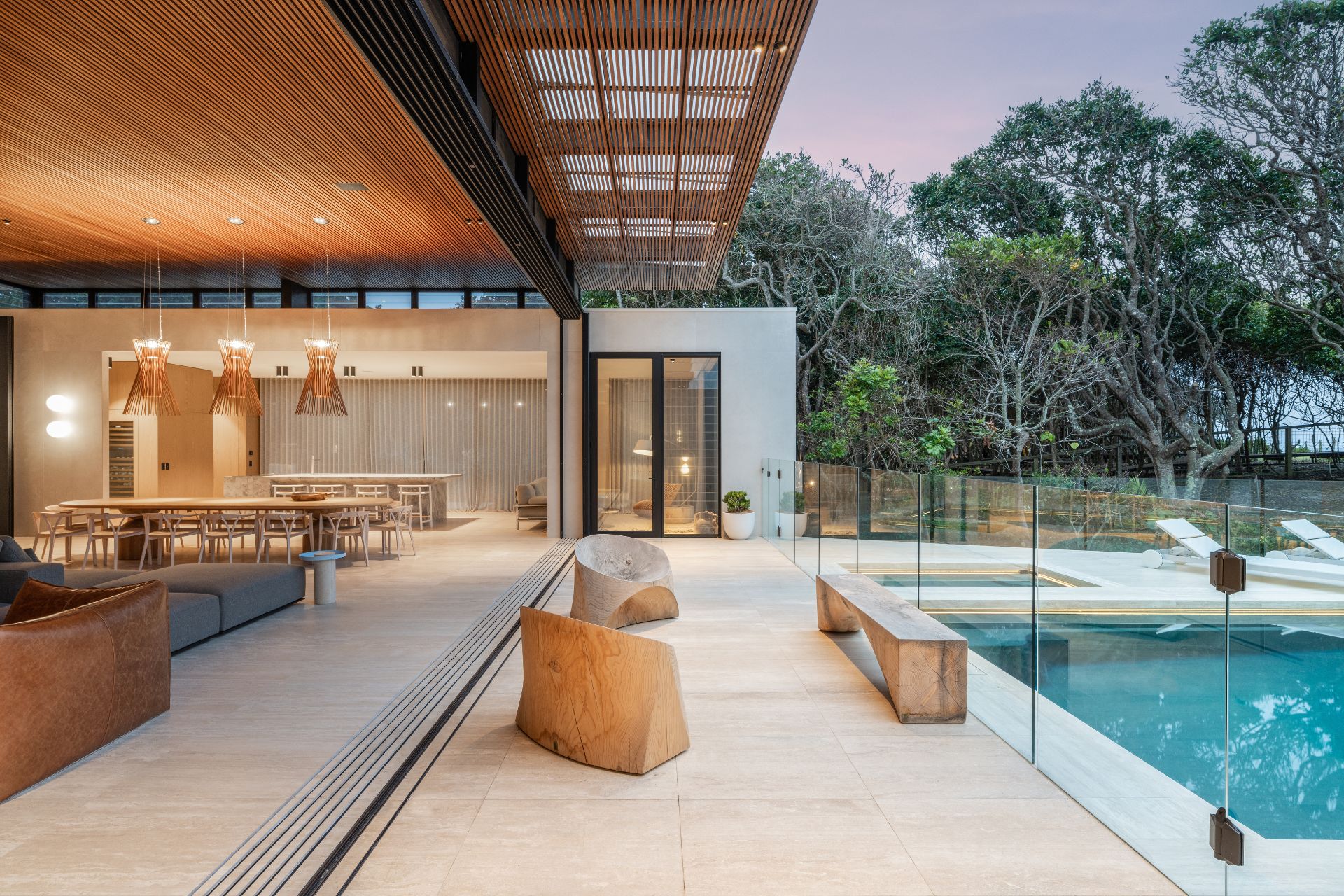 Open plan living room/kitchen with outdoor pool area beside it.