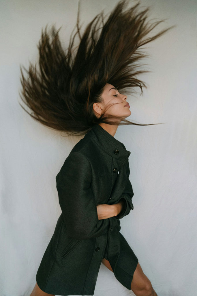 girl with shiny brunette hair whipped above her head