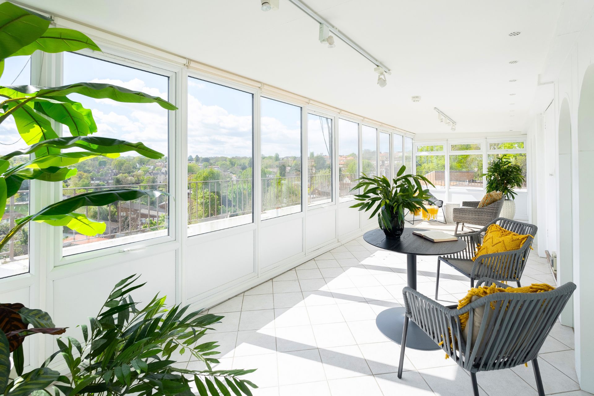 Conservatory with grey chairs, yellow cushions and views over Wimbledon