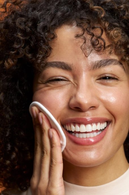Woman wiping face with cotton pad