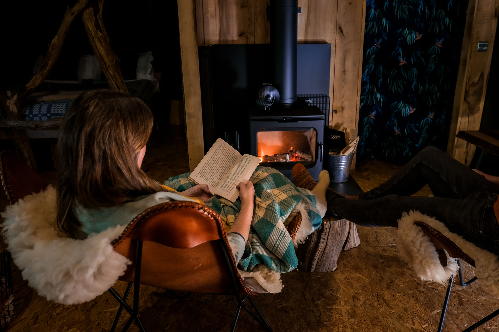 A woman reading a book by the fire