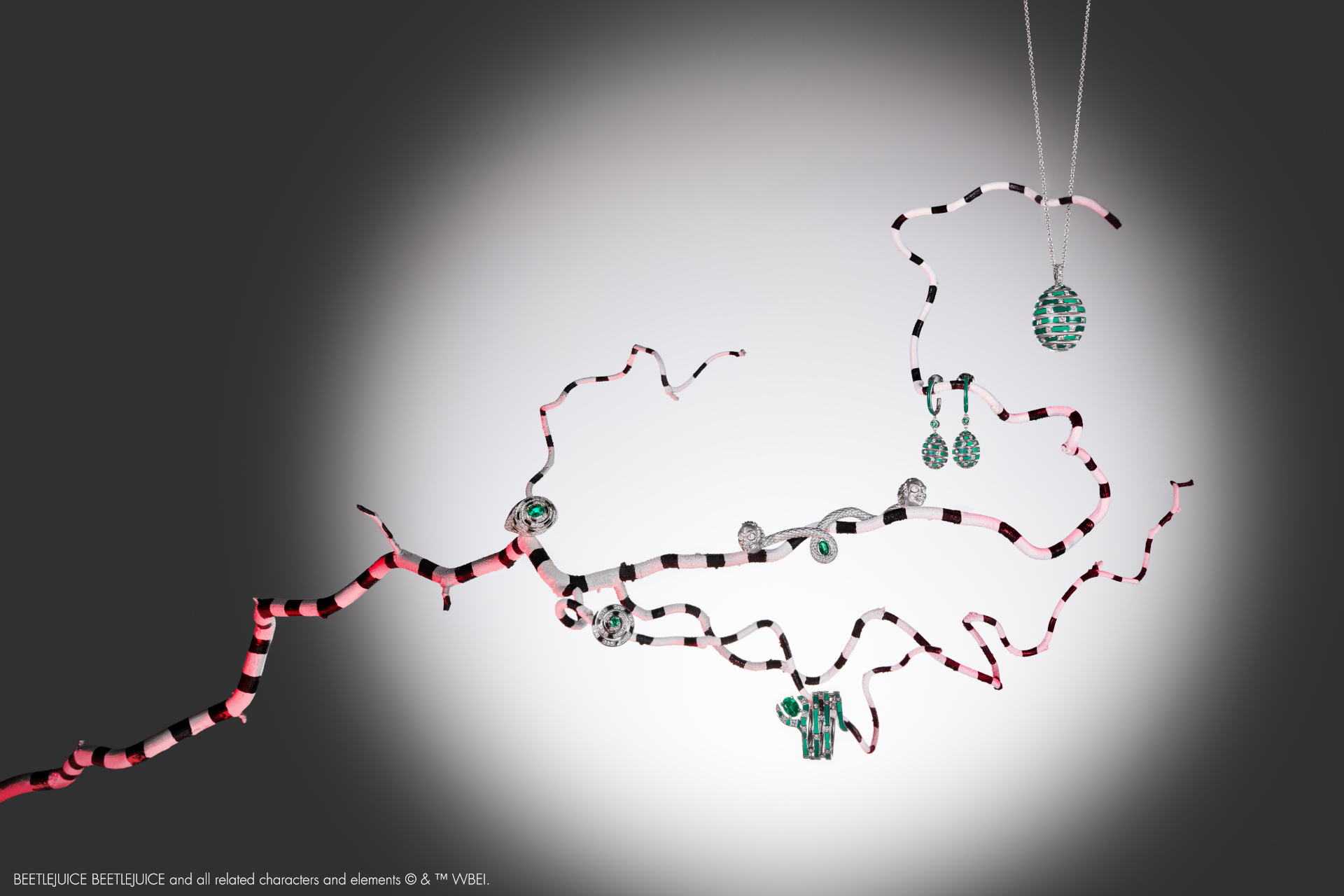 Jewellery layered on striped branch over spotlit background