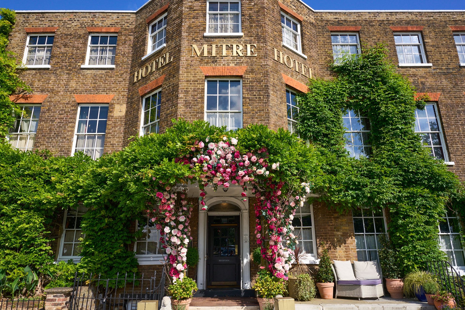 Exterior of The Mitre hotel, with a flower-clad facade.