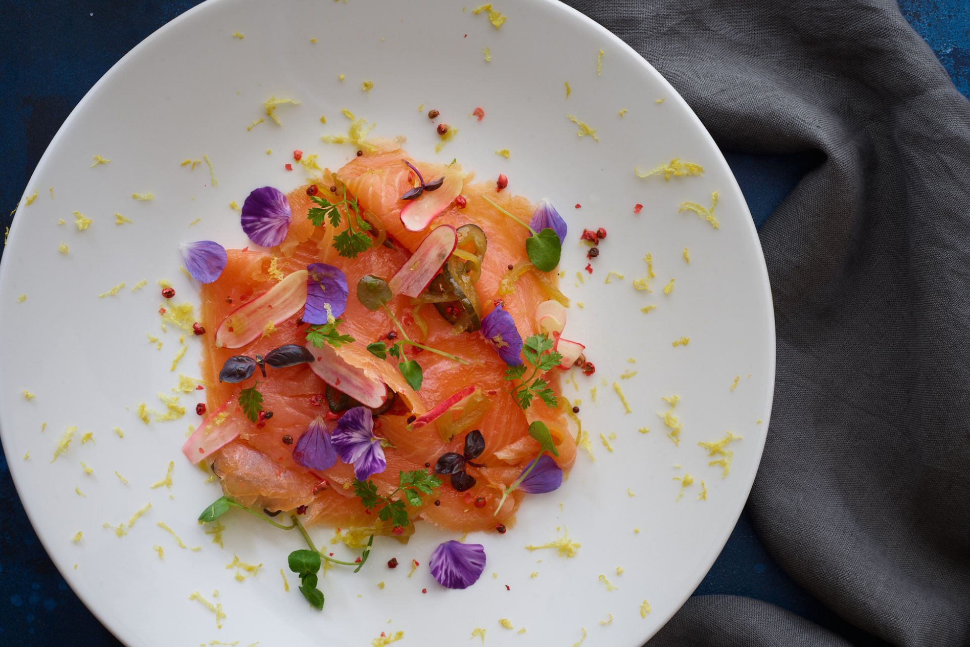 Aerial shot of smoked salmon dish topped with purple flowers
