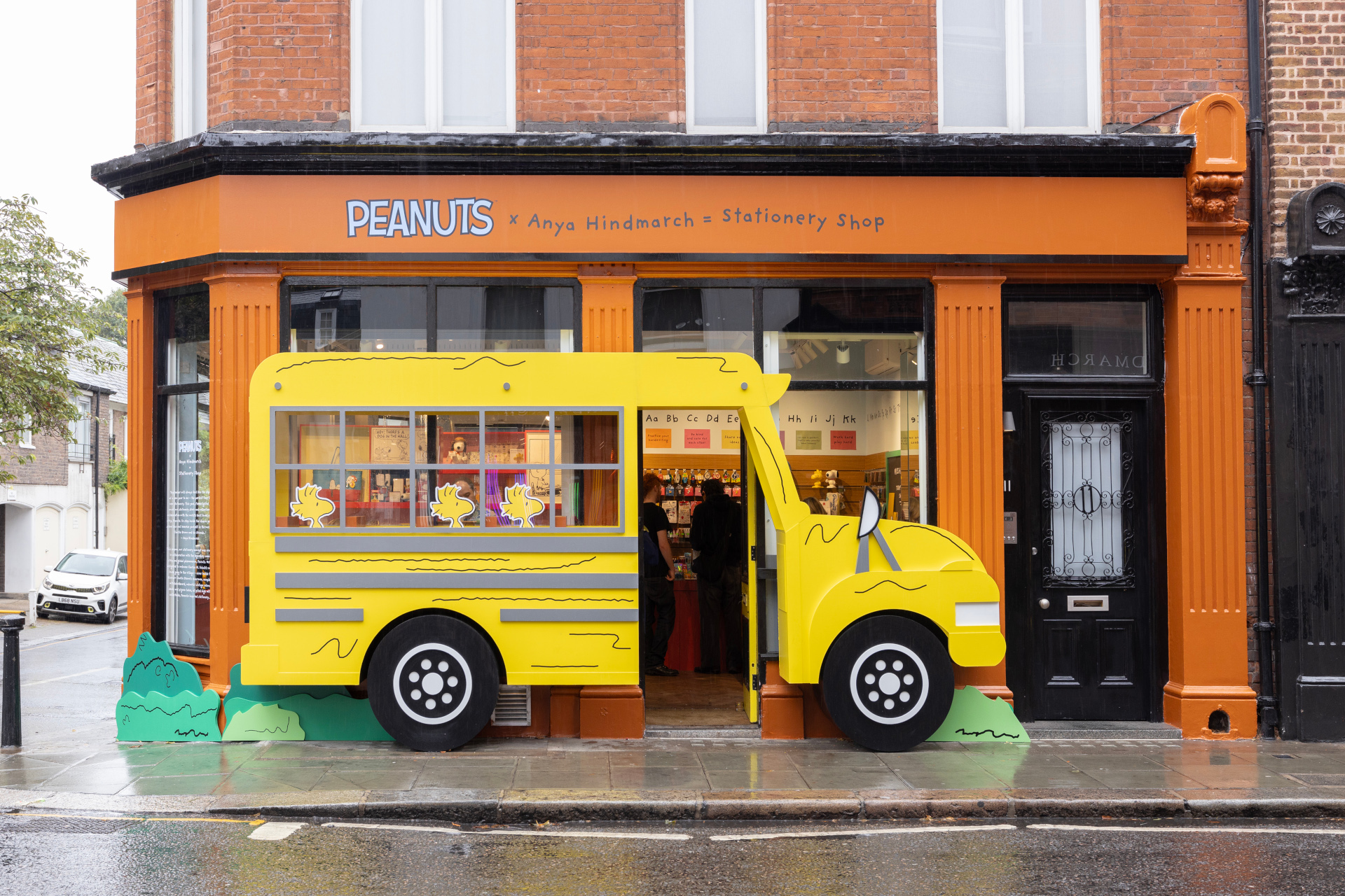 Yellow bus attached to orange shop front | Peanuts x Anya Hindmarch Pop-Up
