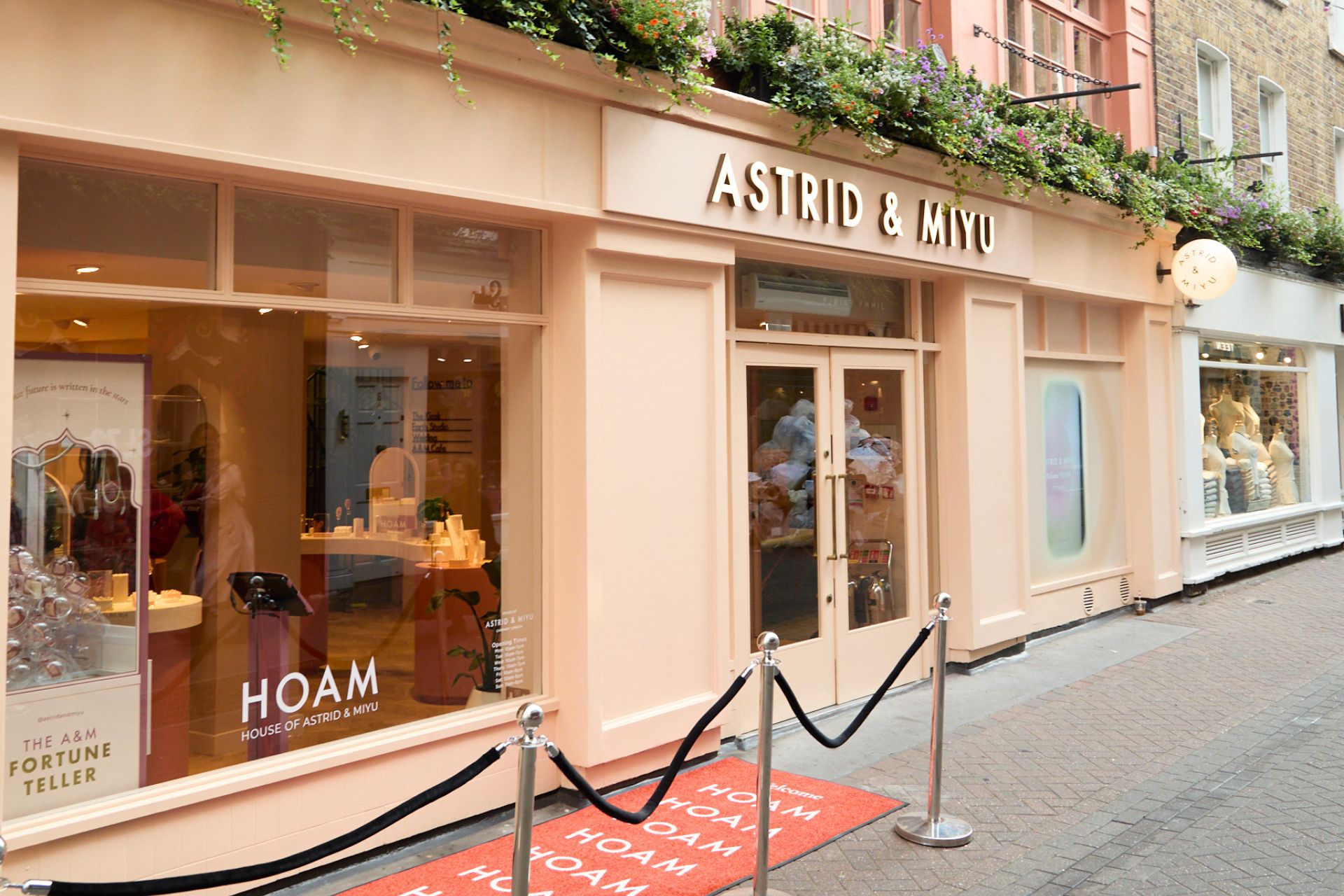 Pale pink exterior of astrid & Miyu store, with flower garlands at the top.