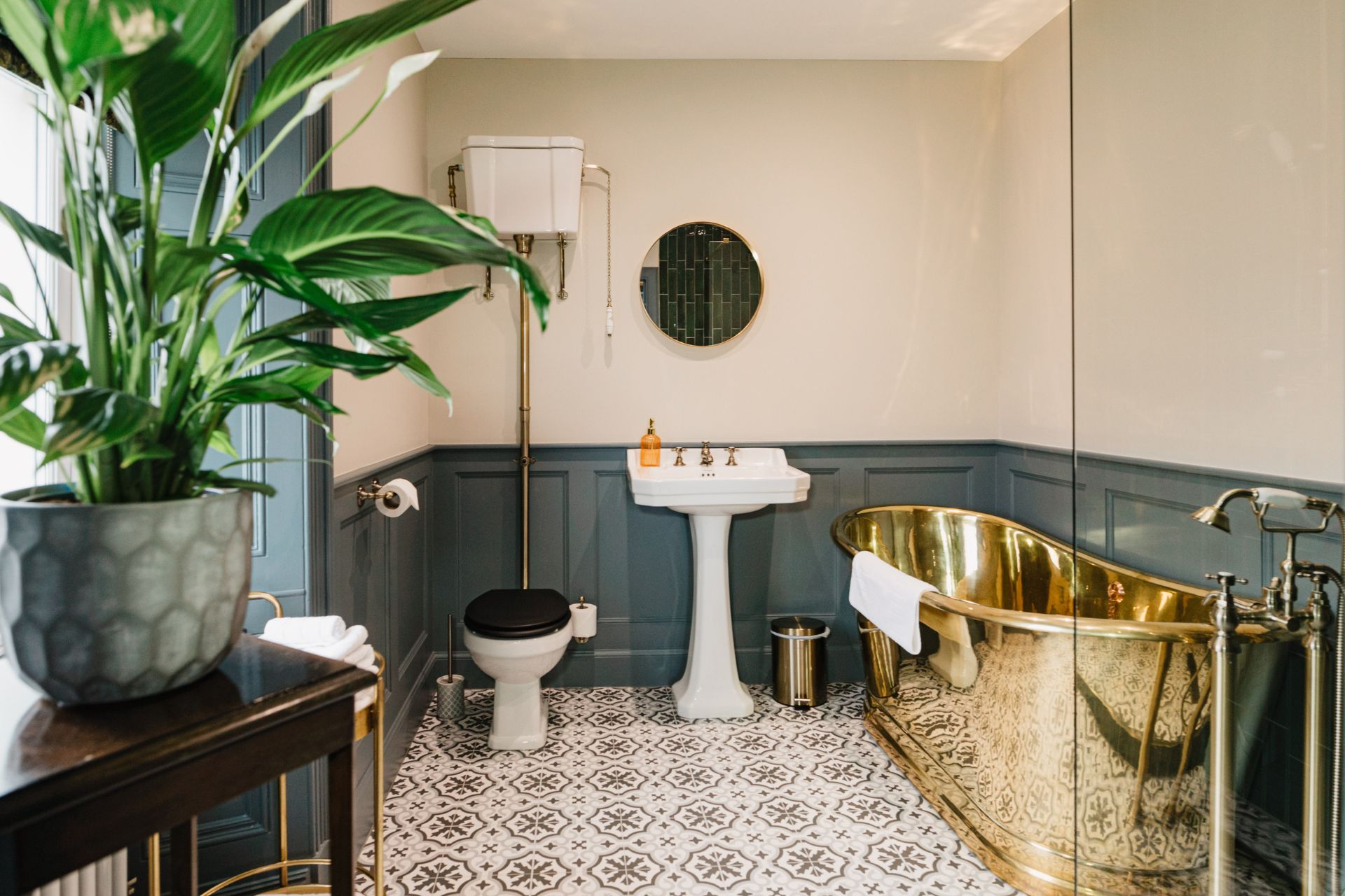 Hotel bathroom with gold bathtub and blue panelled walls