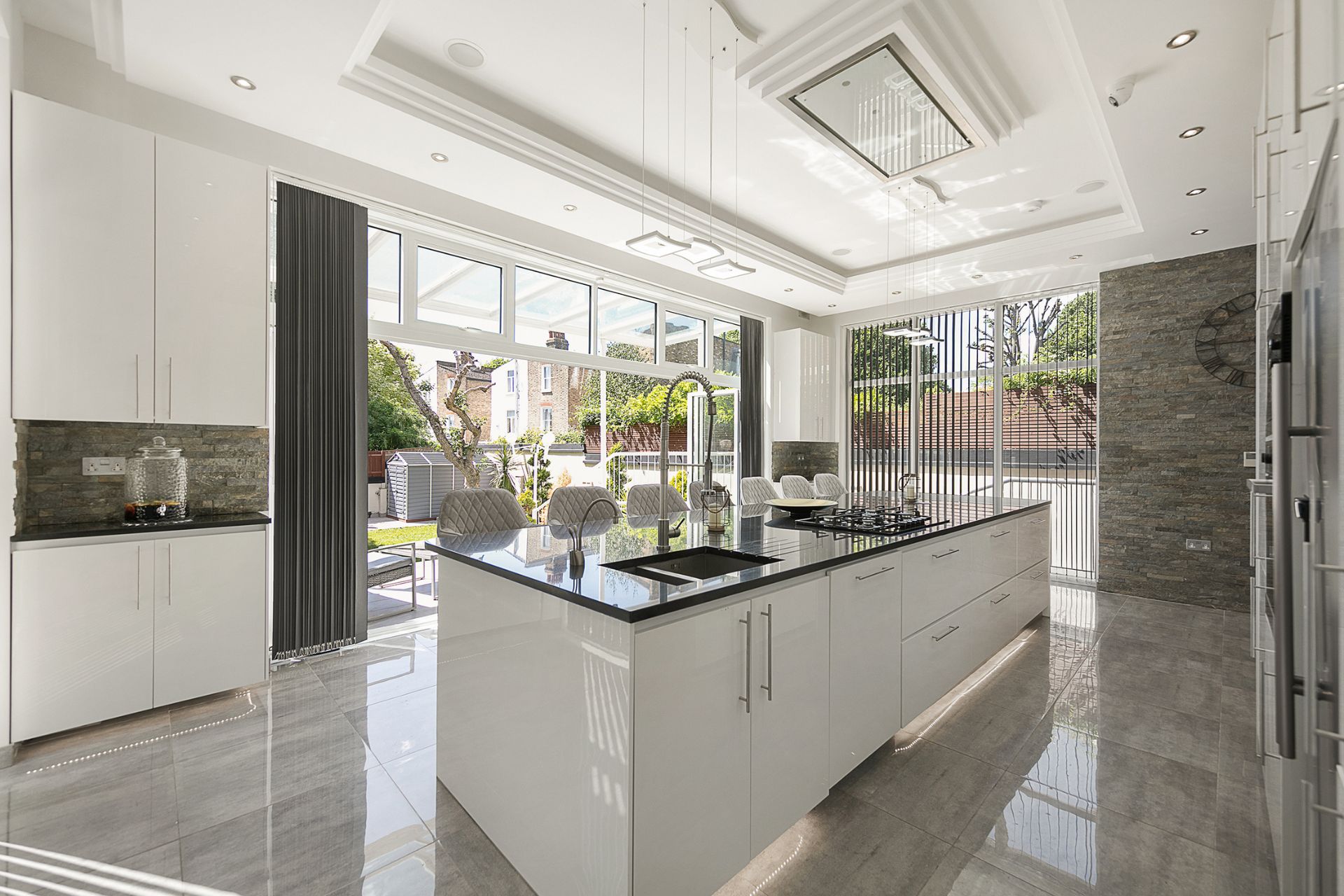 Modern white kitchen with black worktops and a large central island