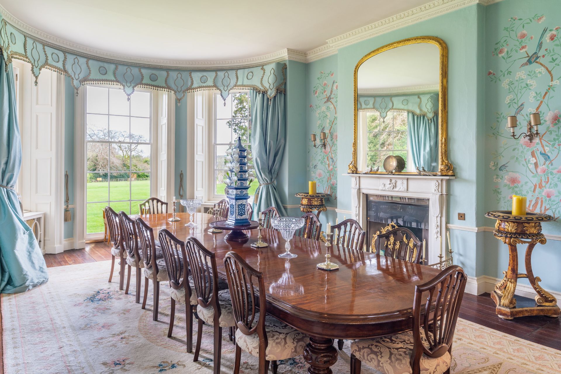 Dining room with pale blue walls, a fireplace and floor-to-ceiling windows