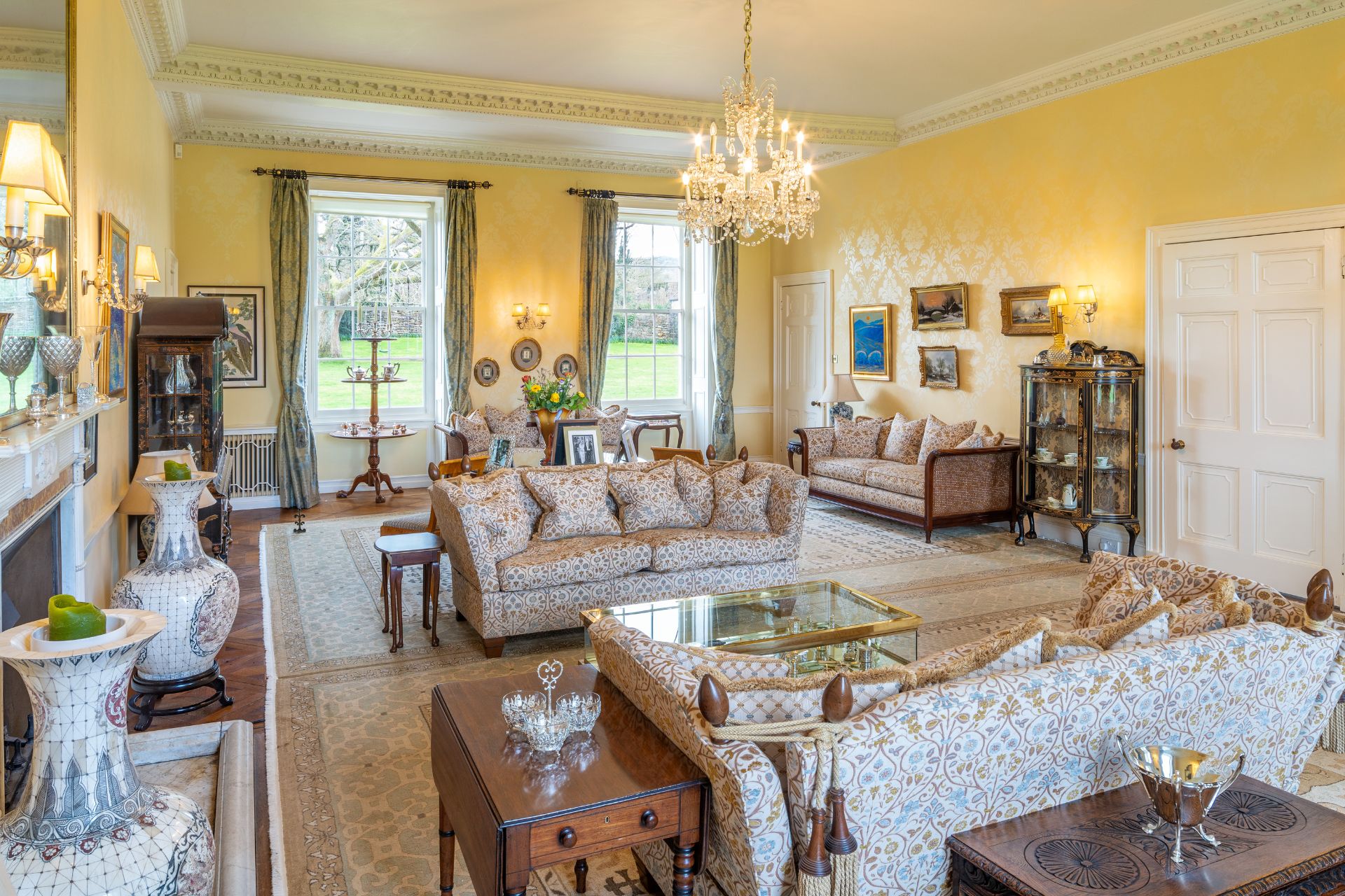 Living room with chandelier, floral sofas and French windows