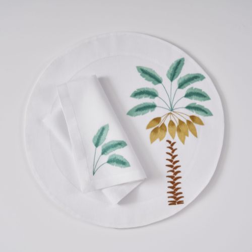 Round white placemat with palm tree motif, and matching napkin