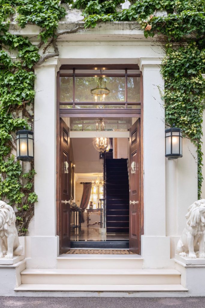 Mansion doorway with marble lion sculptures, Roman archway and an ivy-covered facade