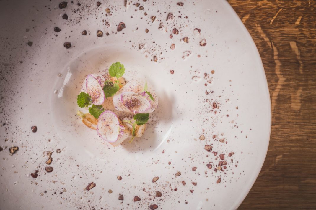 Aerial view of crab dish with turnip and sunflower seeds.