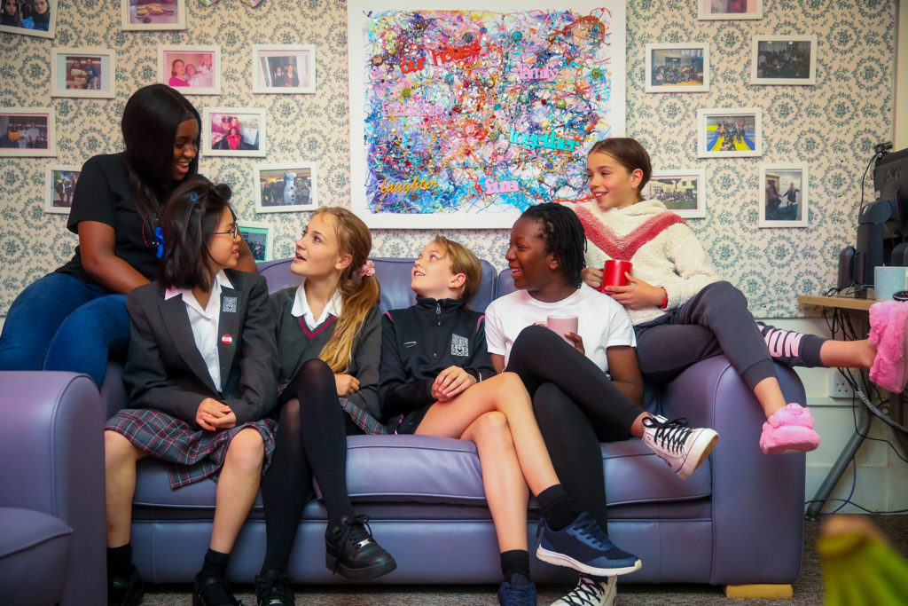 Five students laugh on a couch.