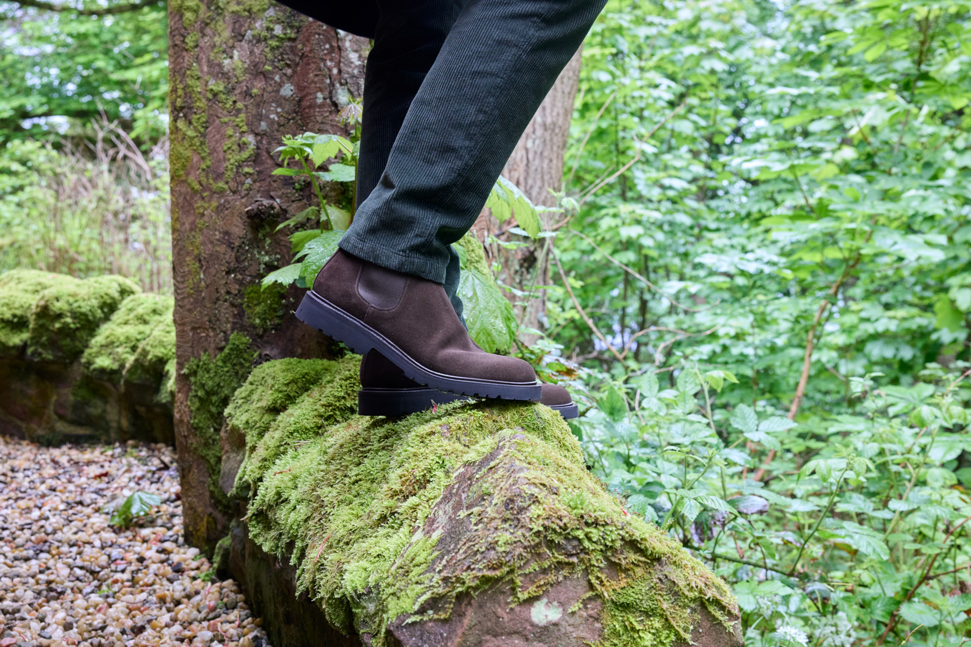 Close up of someone stood on mossy rock next to greenery