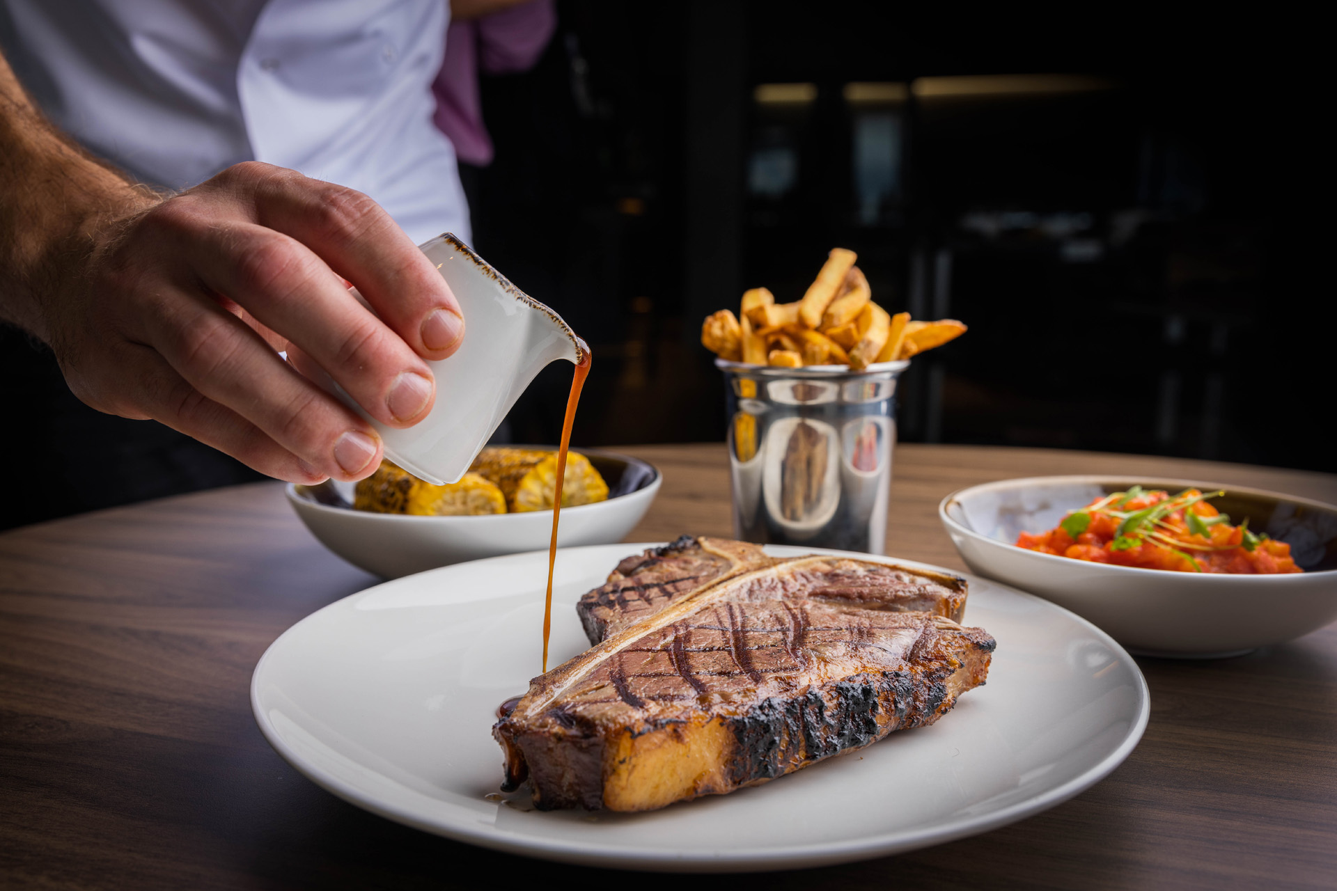 Chef pouring sauce on a steak