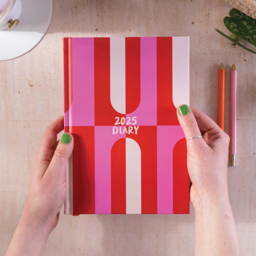 Hands holding pink and red diary