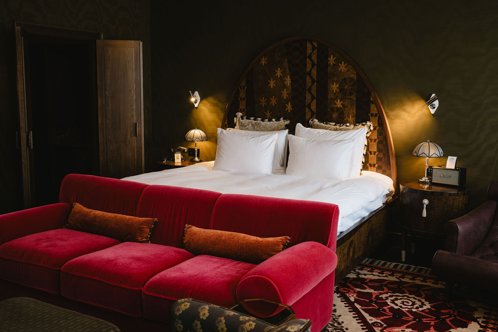 A bed with a red velvet sofa in front