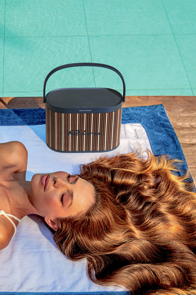 Bang & Olufsen Riva speaker - model lies on a towel poolside next to this outdoor speaker