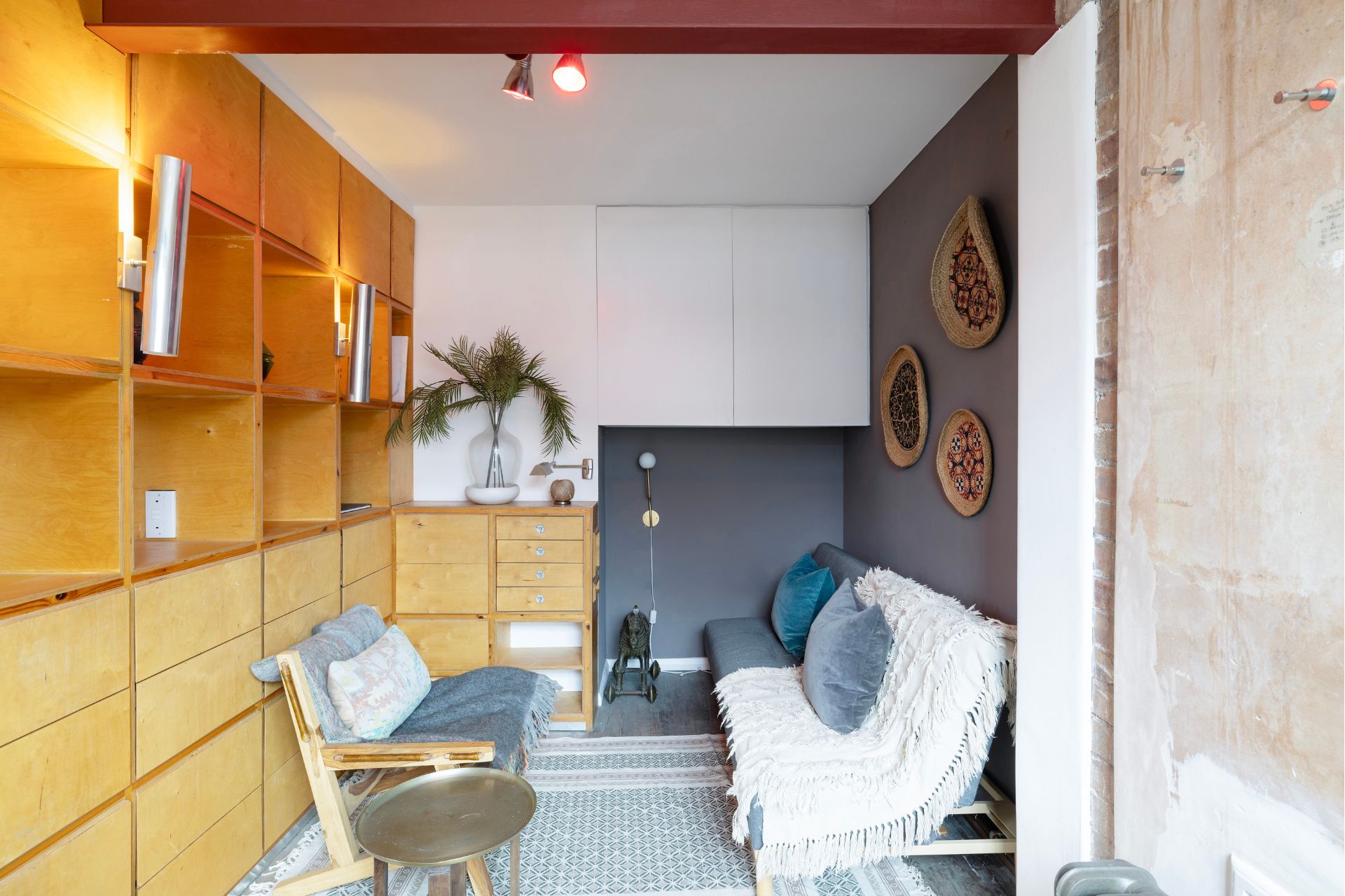 Studio with wooden cupboards, grey walls and a grey sofa.