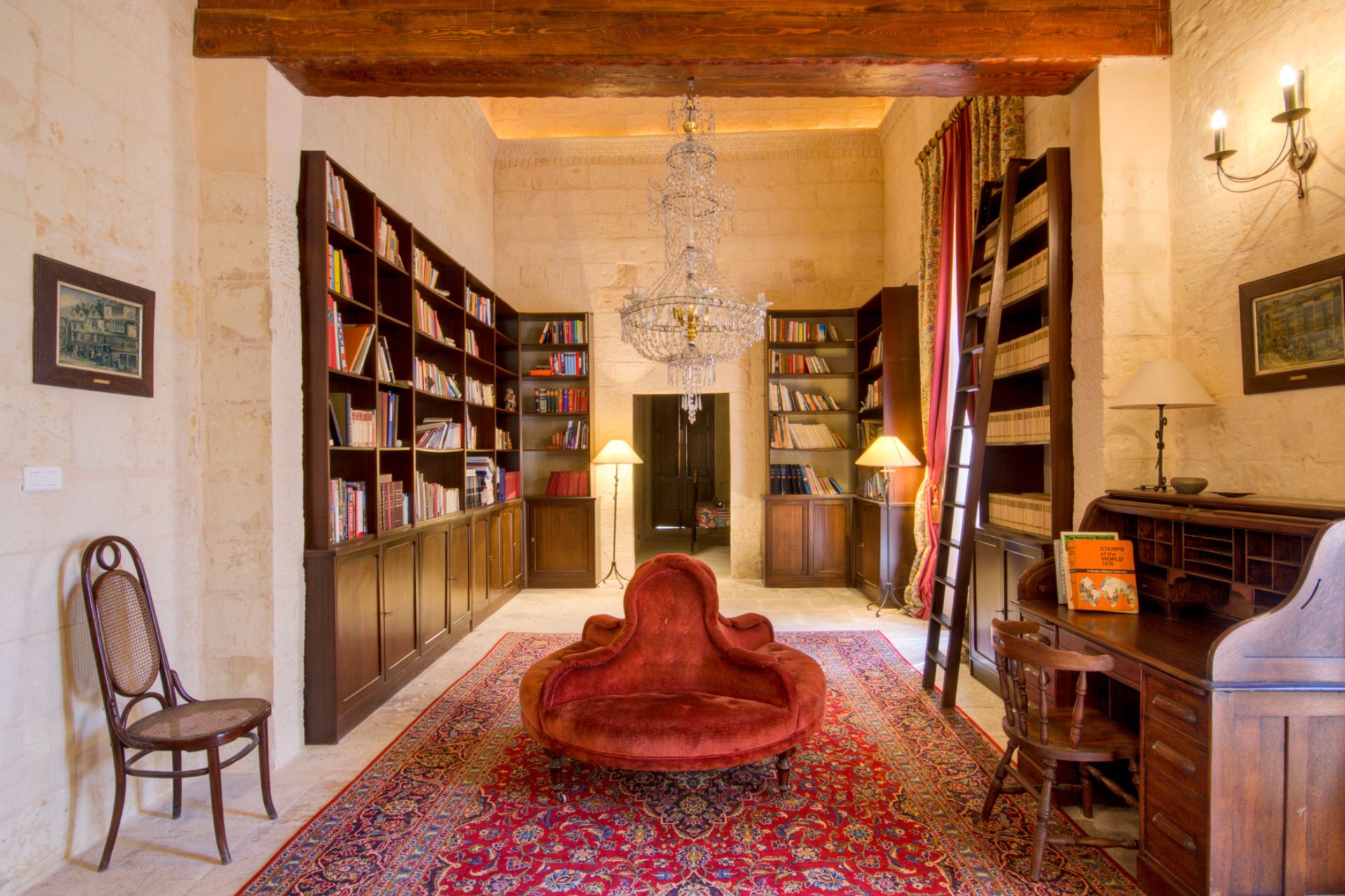 Stone library with wooden bookshelves, Persian rug and chandelier