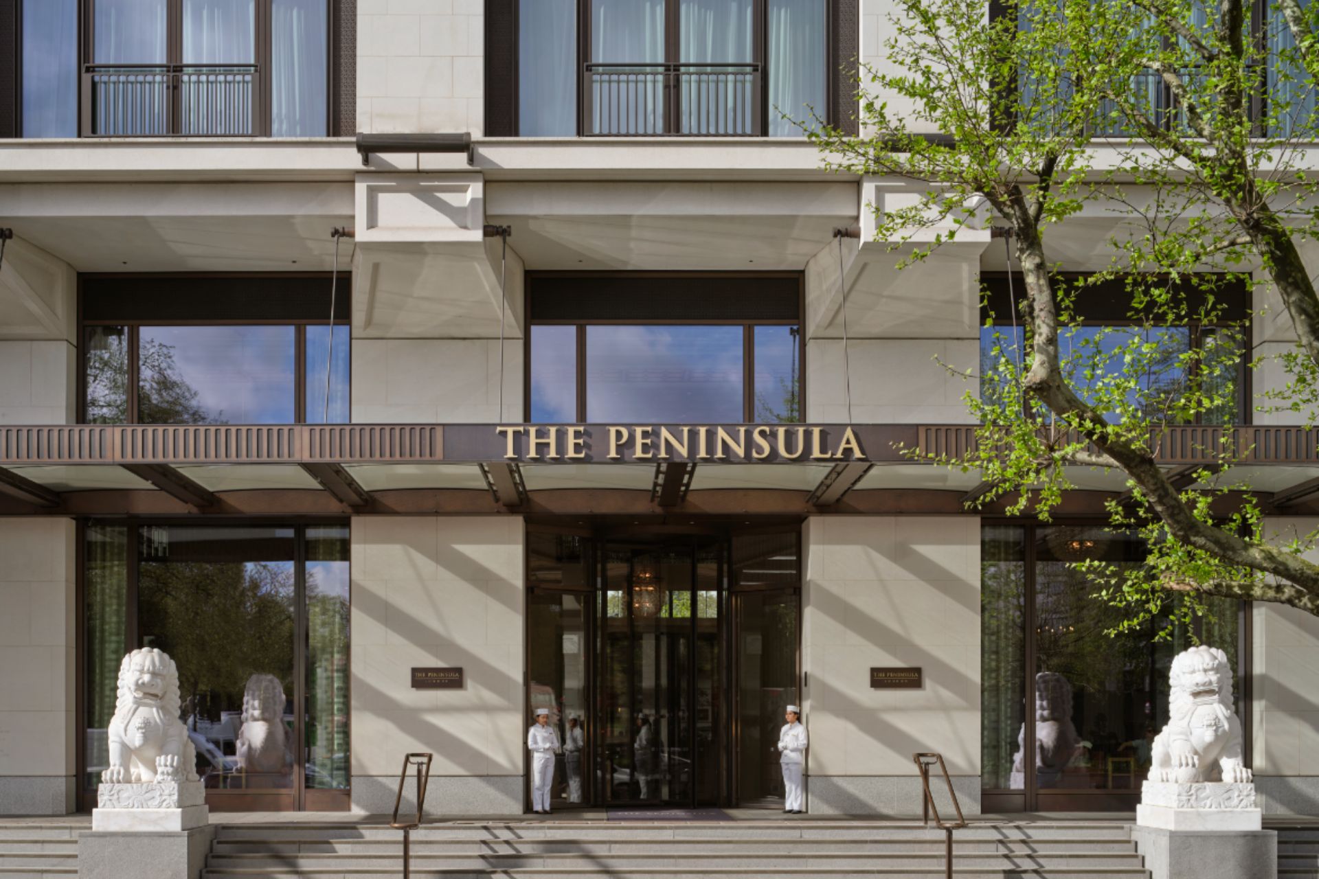 Exterior of The Peninsula London, with stone lions at either side of the entrance.