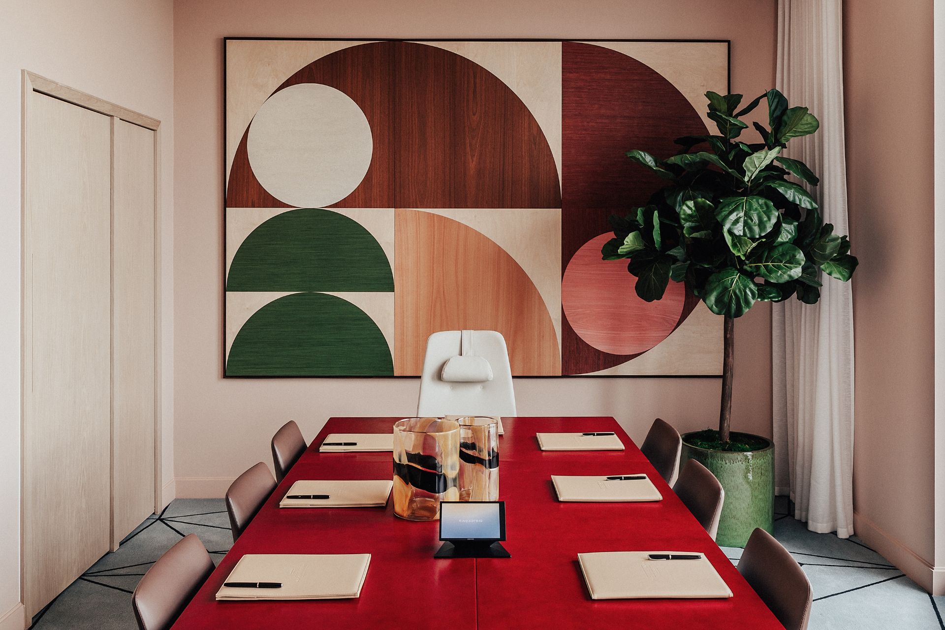 Boardroom with red leather-topped table and geometric wooden art piece