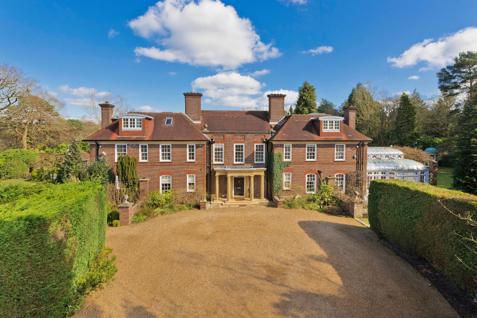 Large red brick home with gravel driveway.